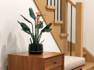 A brick-built flowering plant on top of a set of drawers that is part of a hallway bench set near stairs leading up to the second floor of a house.