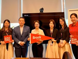 A group of people pose holding Brock branded materials.