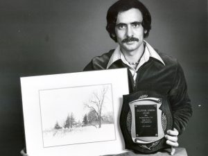 Divino Mucciante poses with an award and photo print. 