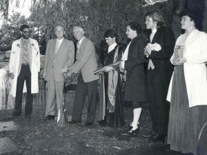 A group of people participate in a sod turning ceremony for a construction project.