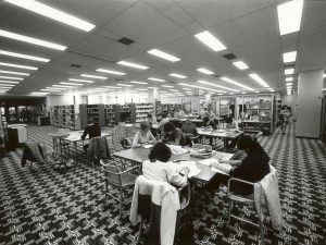 Students sit at tables in a library.