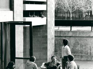 Students sit outside a residence building.