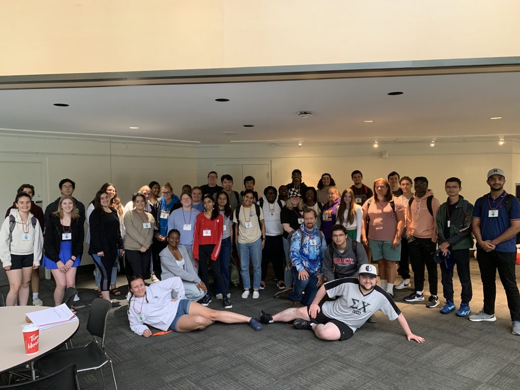 A group of young adults poses in a large room.