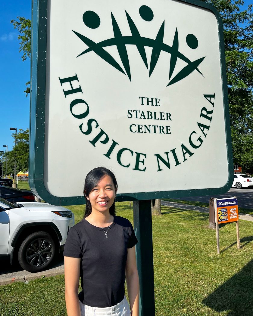 Brock University graduate student Chloe Tse standing outside in front of the Hospice Niagara building.