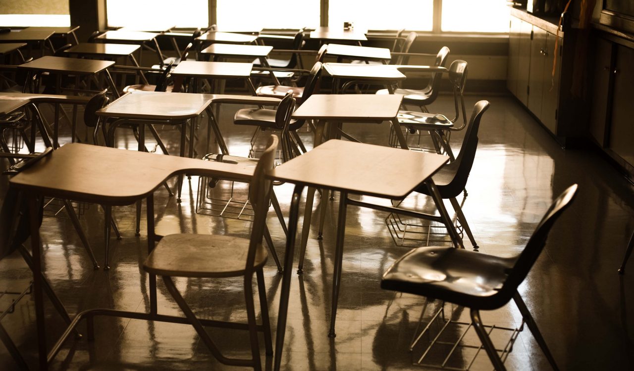 Empty desks are seen in a classroom.