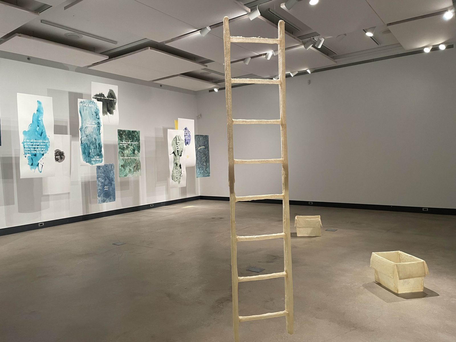Artwork shaped like a ladder hangs in an art exhibition.
