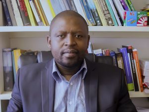 A headshot of Professor Sandile Motsa, Dean of the Faculty of Science and Engineering at the University of Eswatini, in front of a bookshelf.