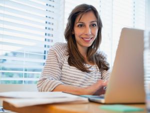 Woman sitting indoors in front of laptop.