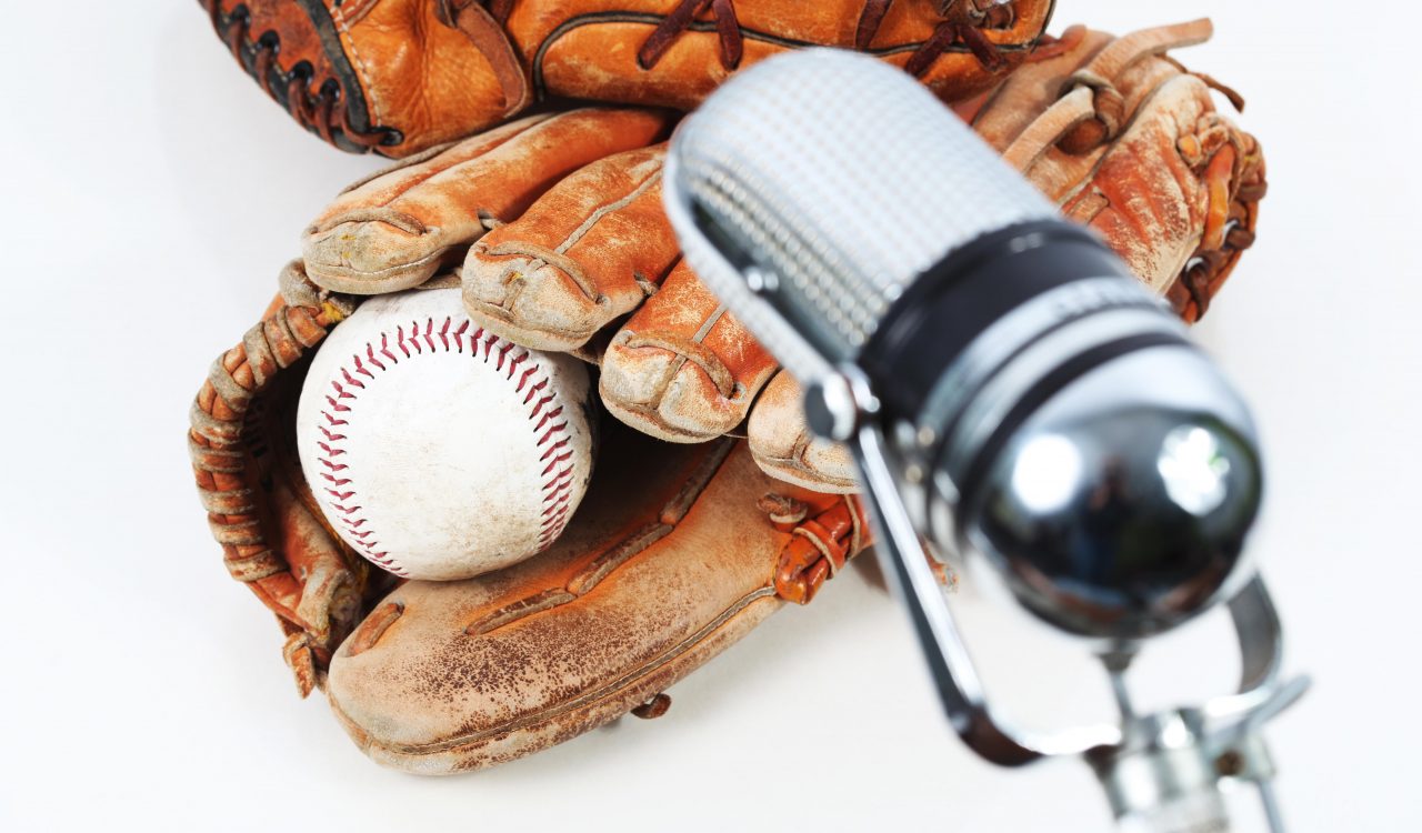 Two baseball gloves, baseball and a microphone against a white background.