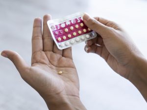 Close-up of young woman's hand holding birth control pills