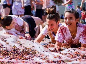 A group of women slide into a mess of grapes while laughing.