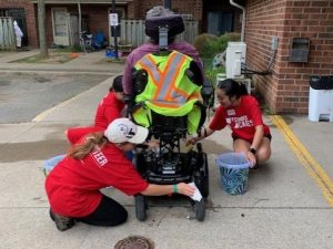 Three young people clean a wheelchair.