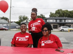 Three young women smile while posing for a photo behind a table.