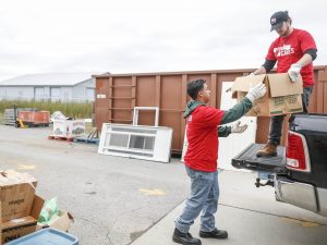 Two young men load boxes onto a truck.