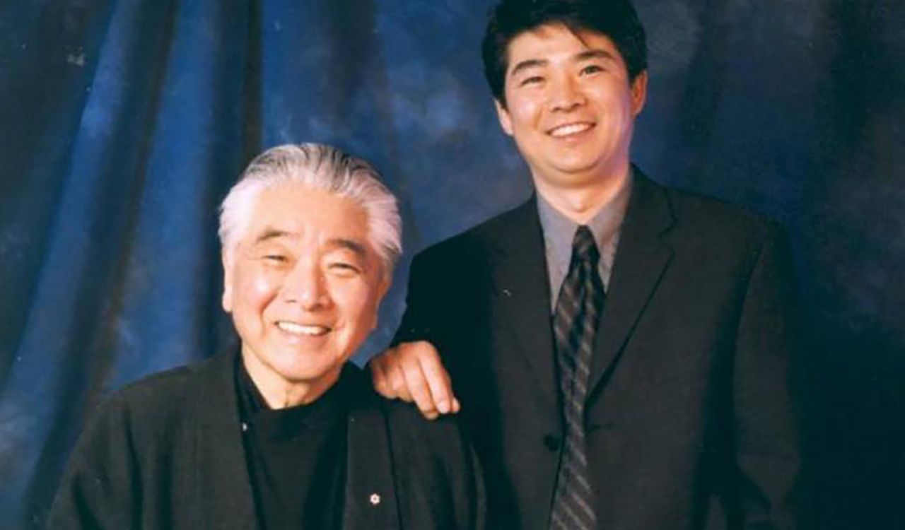 Two men pose together.