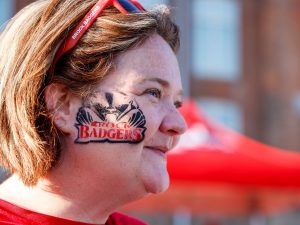 The side of a woman's face features an airbrushed face painting of a Brock Badgers logo.