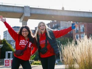 Two women in Brock University sweaters celebrate outdoors.