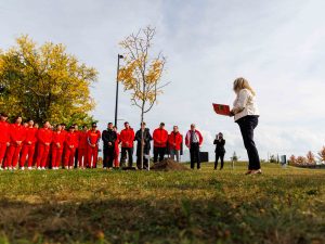 Melissa Krist, Executive Director of Brock Sports and Recreation stands in front of a tree surrounded by the Chinese women’s national hockey team.