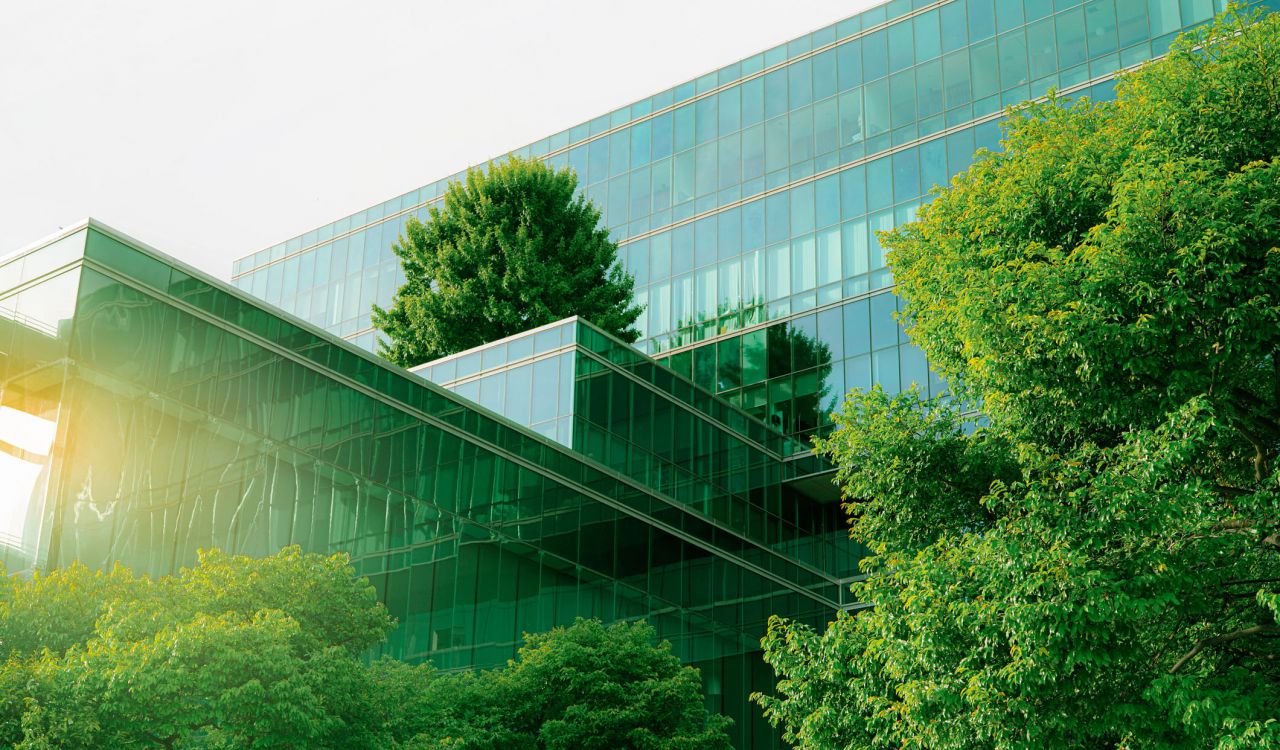 A glass office building with trees on and around it.