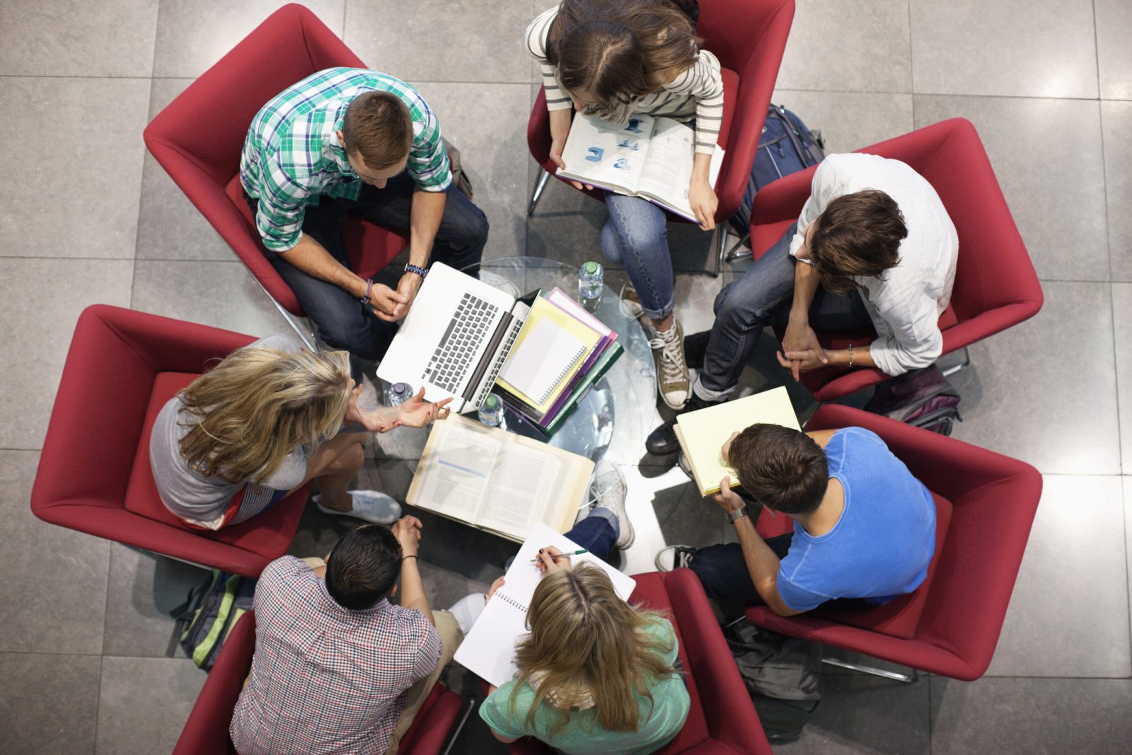 A group of people sit in a study circle with laptops and notepads.
