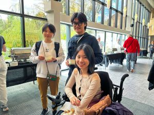 Three university students, one using a wheelchair, attend a food festival.