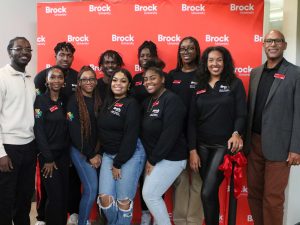 A group of people pose for a photo in front of a Brock University banner.