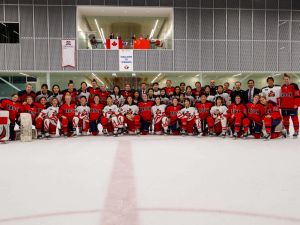 Women’s hockey players from Brock University and Team China pose for a group photo at centre ice at Canada Games Park.