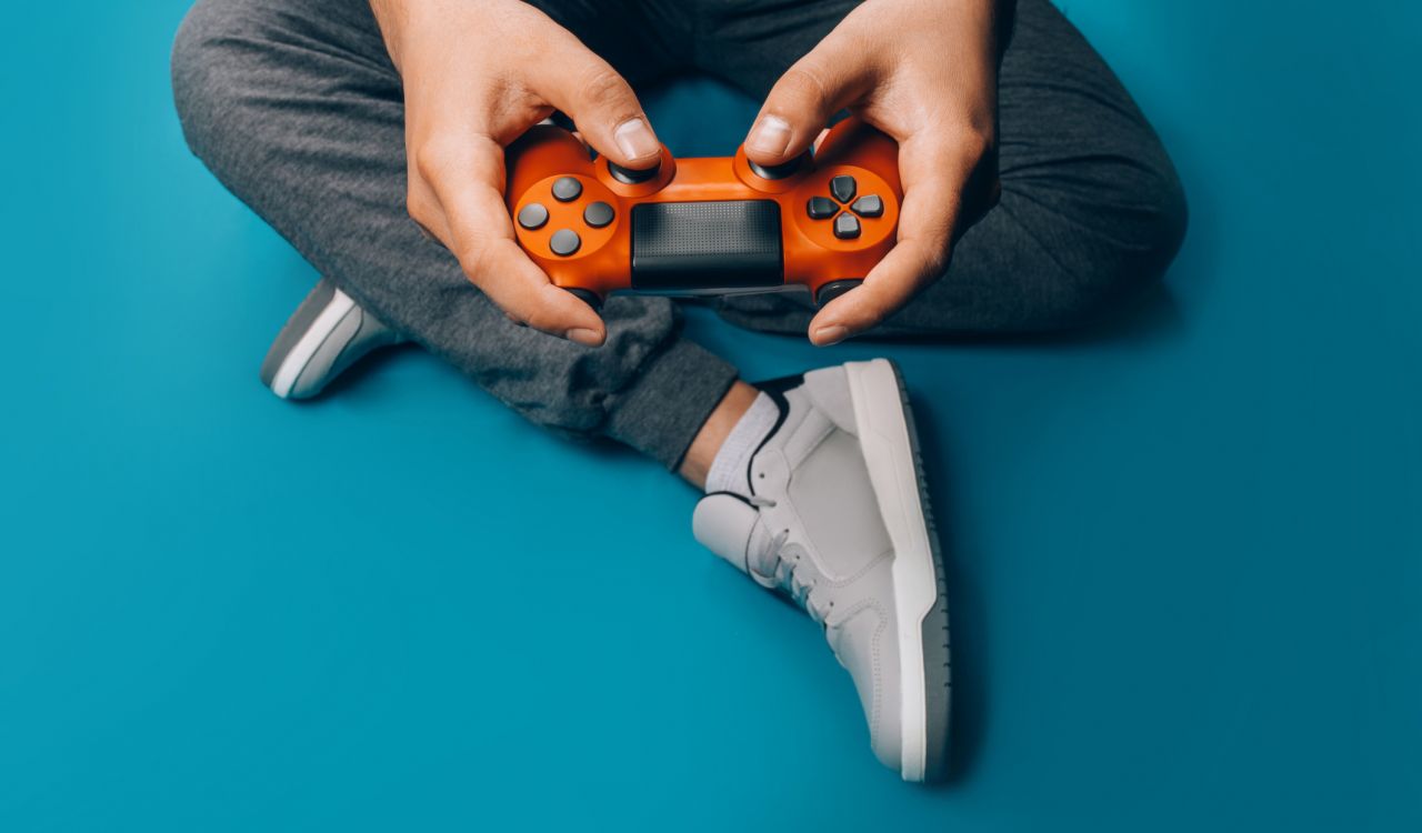 A person sits cross-legged on the floor with a video game controller in their hands.