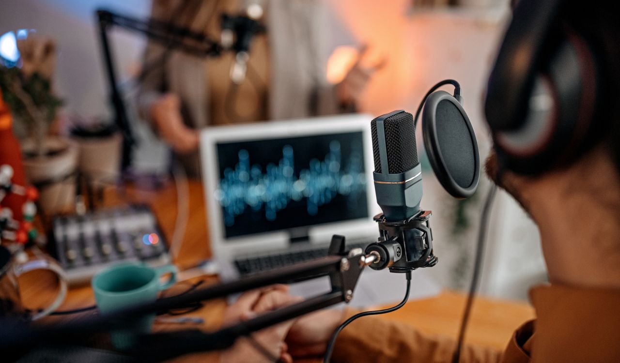Selective focus of microphone used by young man and woman while recording in a studio.