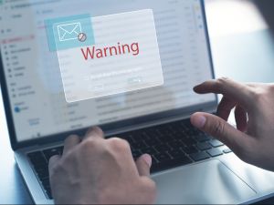Blocking spam e-mail, warning pop-up for phishing mail, network security concept. Business man working on laptop computer at home with warning window on screen