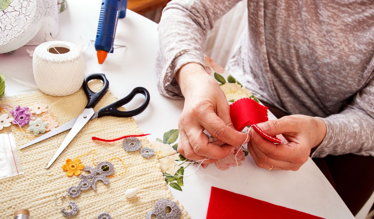 Senior women sews a heart-shaped ornament by hand.
