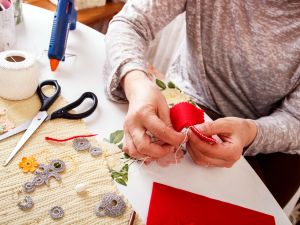 Senior women sews a heart-shaped ornament by hand.