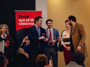 A group of people in business attire pose talk at an event.