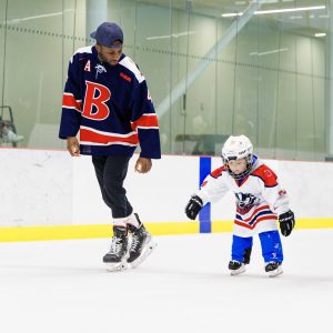 A man skates alongside a child during a community skate at Canada Games Park.