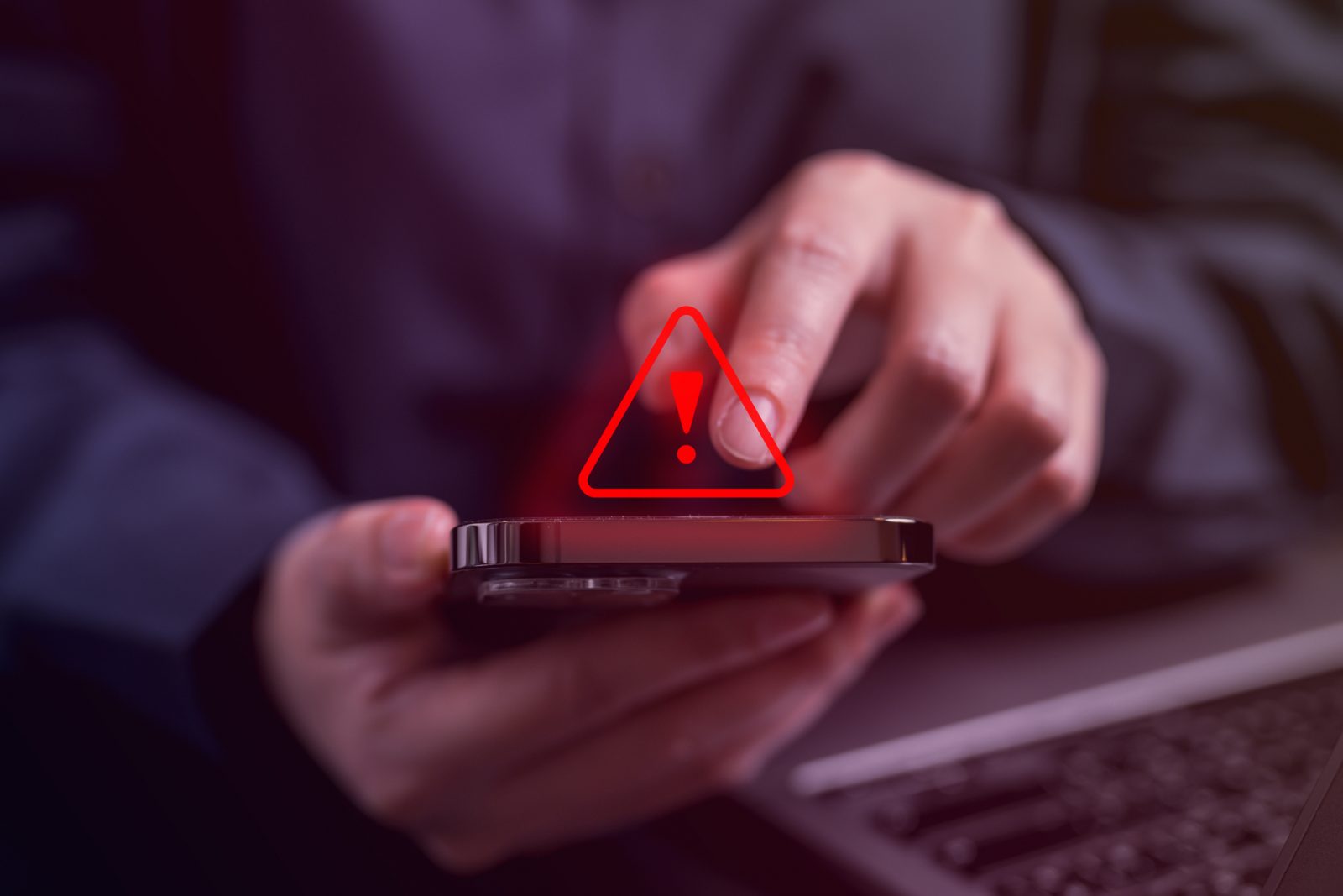 Hands holding a mobile phone with red warning icon hovering over it.