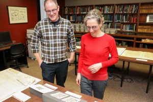 Two people look at medieval parchments in a library.