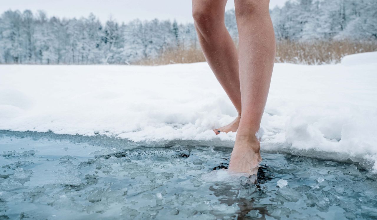 A pair of legs set to step into an area of water cut out of an icy surface.