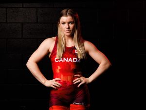 Brock wrestler Hannah Taylor stands dramatically lit while wearing a Canadian wrestling uniform in a dark room.