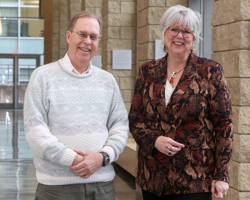 Peter Tiidus and Mary-Louise Vanderlee stand next to each other in a large hallway at Brock University.