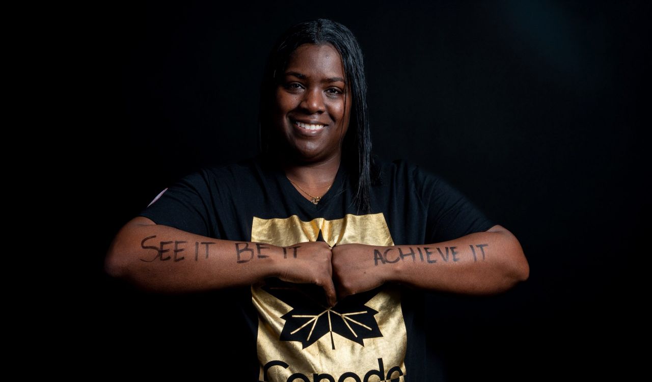 Shauna Bookal holds her arms in front of her chest, knuckles touching each other, to show the message written on her arms, “See it, be it, achieve it.”