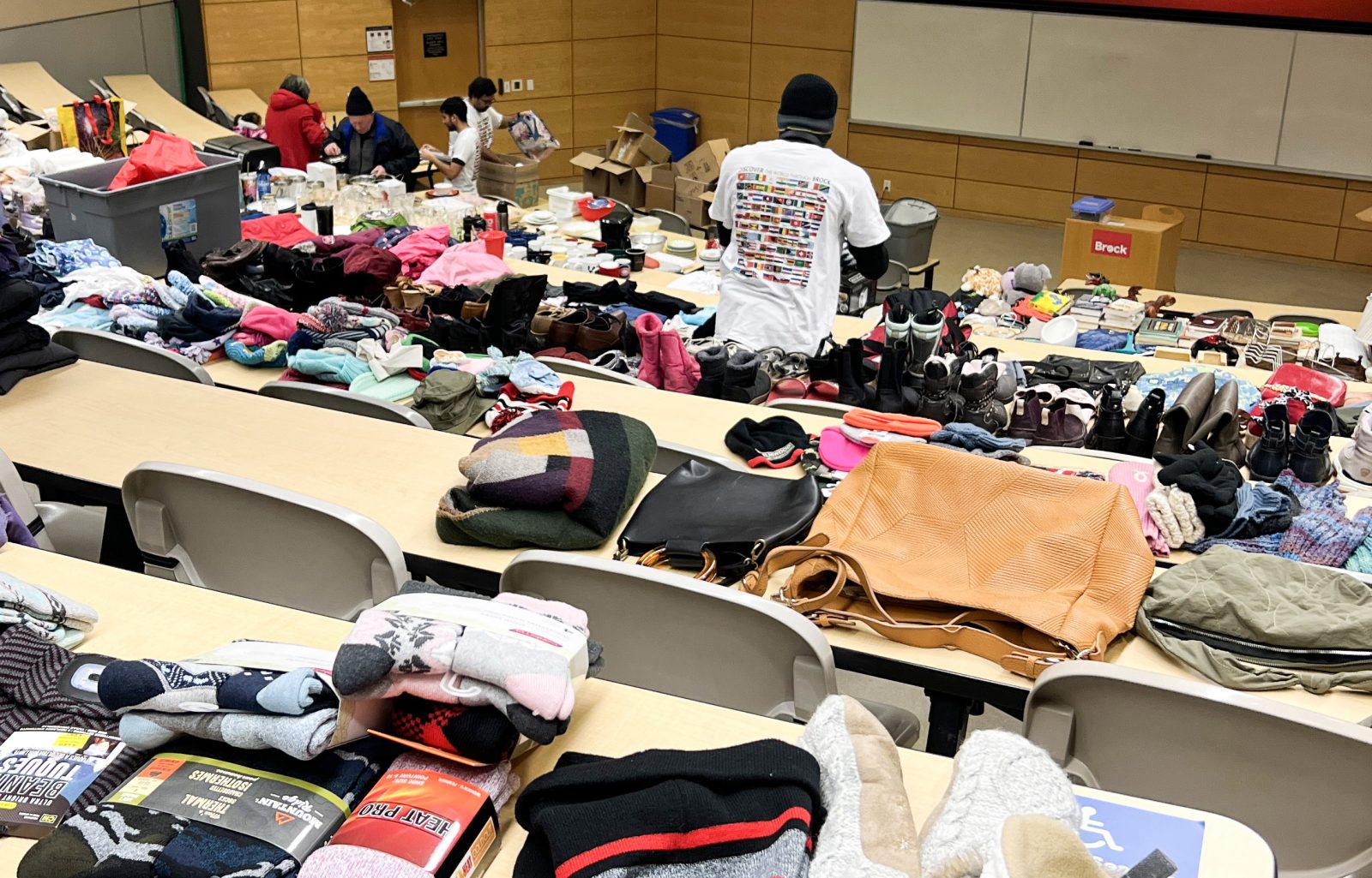 University student volunteers sort through clothing and household items on display.