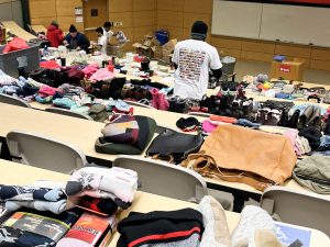 University student volunteers sort through clothing and household items on display.