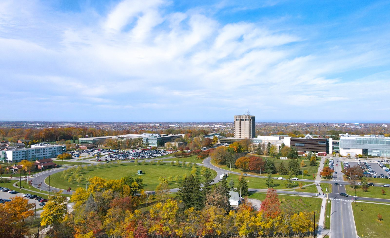 Brock University's main campus seen from an aerial view with an abundance of green space and trees in the foreground.