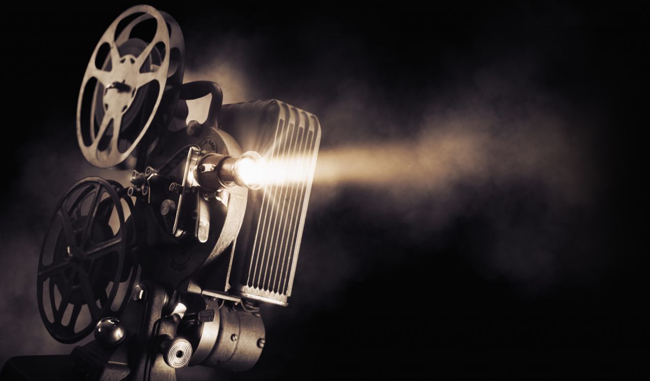 A movie projector with light streaming over a dark background.