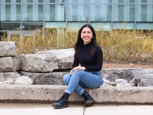 Shamae Quinquito sits on a curb outside in a courtyard located near the Walker Sports Complex building at Brock University.