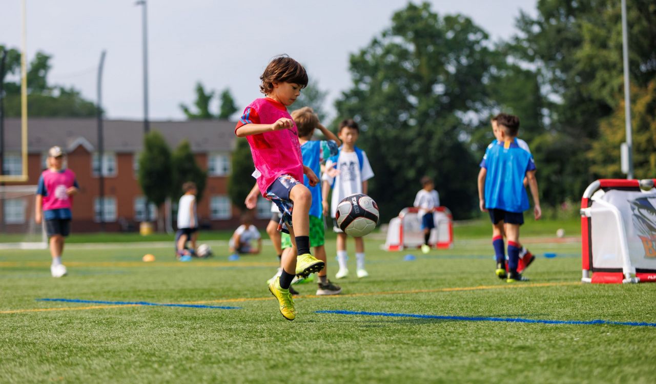A boy kicks a ball on Brock University’s Alumni Field during a soccer sports camp.