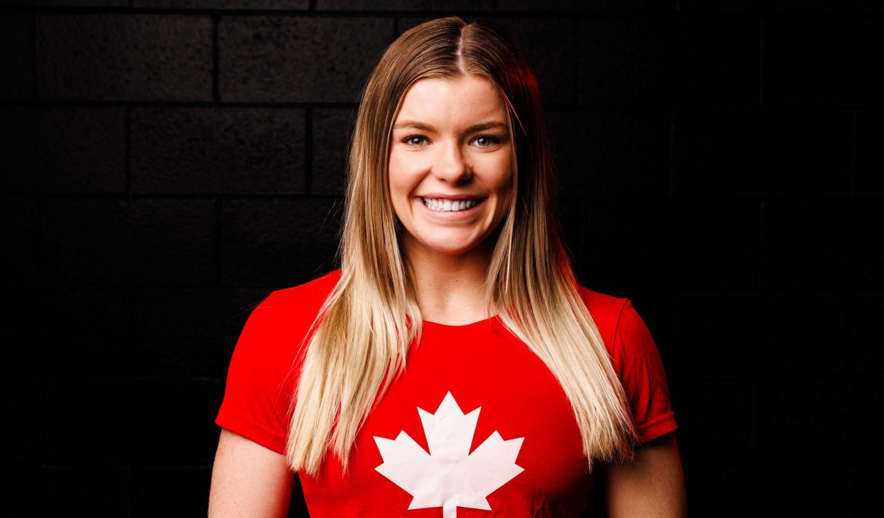 A female wrestler stands proudly wearing a red Team Canada shirt.