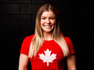 A female wrestler stands proudly wearing a red Team Canada shirt.