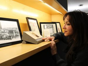 A female student organizes artifacts and picture frames on a display case shelf.