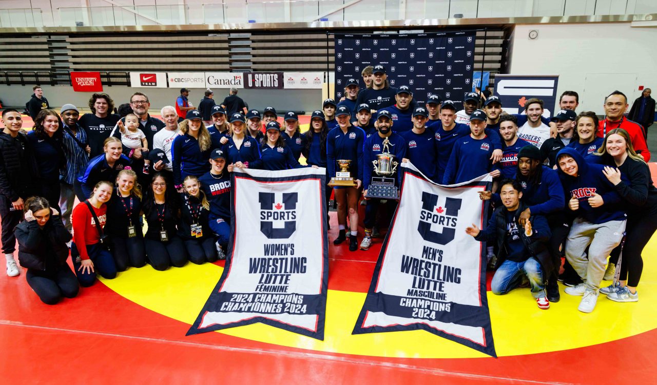 A large group of people pose with two championship banners.